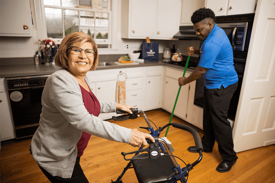 A man sweeping the floor of the house infront of a happy lady